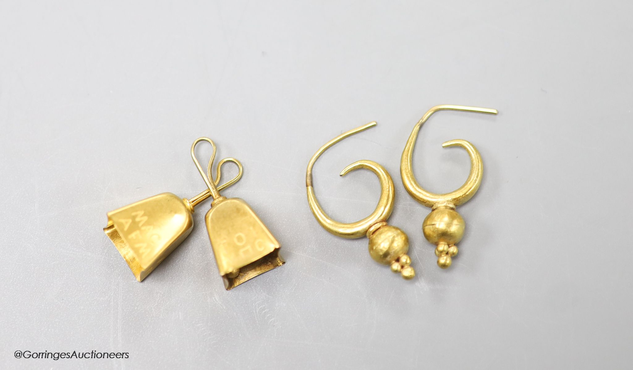 A pair of yellow metal earrings and a pair of yellow metal cowbell charms